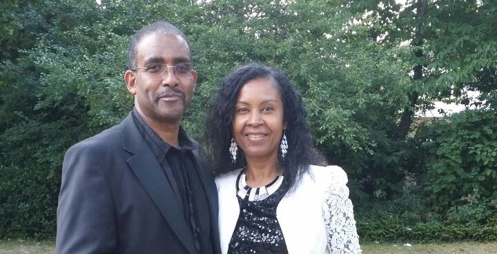 Couple posing for a photo in front of some foliage