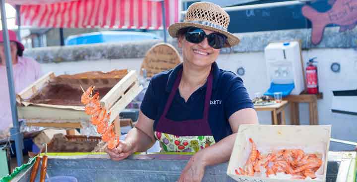 Stallholder at Streatham Food Festival holding a skewer of prawns