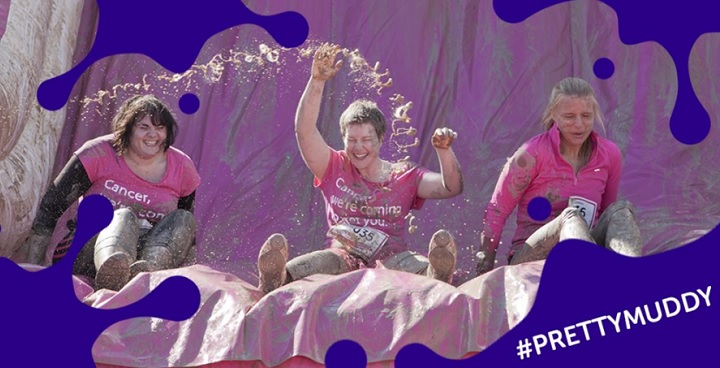 Image of people sliding down a muddy inflatable as part of Cancer Research UK’s Race for Life Pretty Muddy event