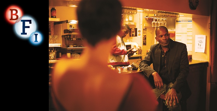 Still image from the film, 35 Shots of Rum. Man sitting at a bar, leaning on it with one elbow and staring into the right.