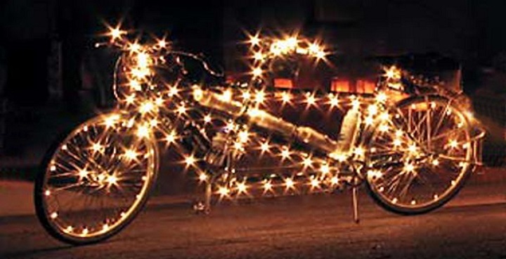 A tandem bike in the dark but lit up with fairy lights along the frame