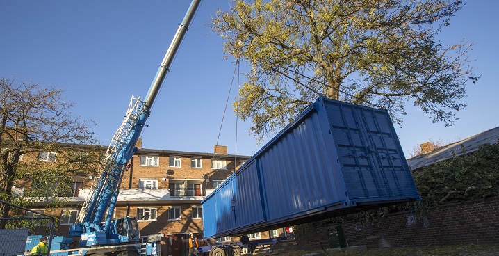 Crane lowering a blue shipping container into position on Brixton’s Solon Estate