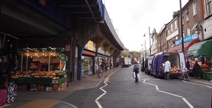 Atlantic Road, railway arches on the left side and vans parked up along the right.