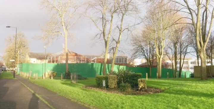 Coburg Crescent as it looks now. viewed from Palace Road. Most of the building works are hidden behind green hoarding and the top of scaffolding around the building is just visible.