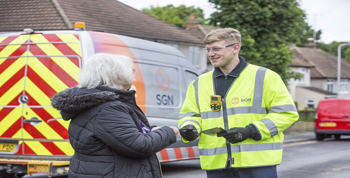 white haired customer talking to SGN operative in yellow hi viz with his SGN branded white van outside bungalow
