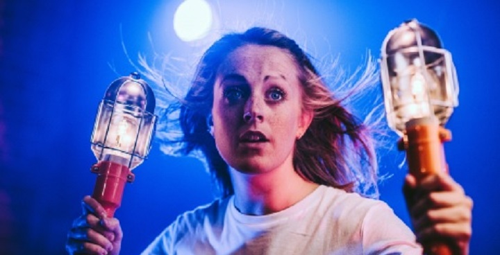 Teenage girl holding a bulkhead lamp either side of her head advertising play about time travel