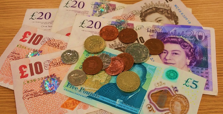 A pile of bank notes and coins of various denominations.