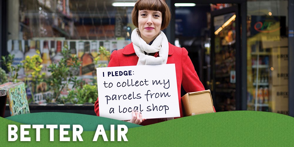 Lady in a red coat holding a Better Air Pledge, which reads: "I promise to collect my parcels from a local shop""