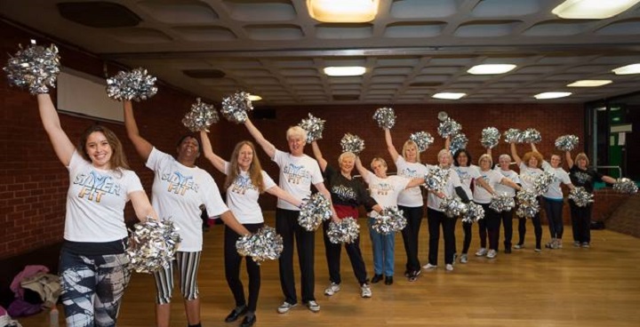 'chorus line' of over 45s - men and women - with 'silver fit' branded t shirts and silver foil pom poms held high in right hand and low in left hand