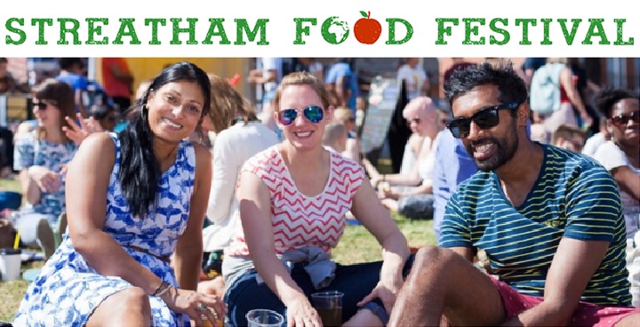 Three people sitting on the Streatham Green grass, holding a drink and smiling. Many people are around them. Caption above reads "Streatham Food Festival"
