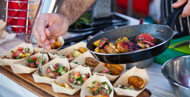 Chef spooning fried diced vegetables and chicken into taster bowls.