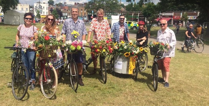 Group of riders in a row with their bikes decorated with flowers and plants