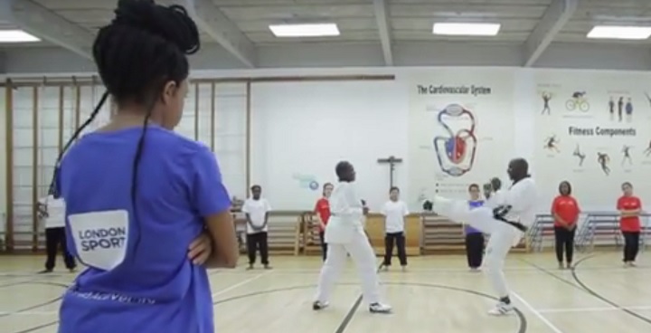 Group of children standing in a circle being taught a martial art