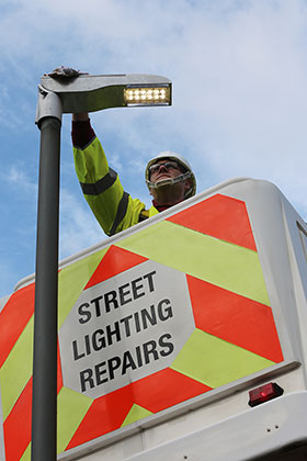 Man in high-viz clothing installing a new sodium bulb