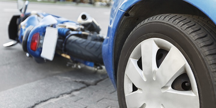 An imagine showing a collision between a blue car and a blue motorcycle, with the motorcycle lying on the floor