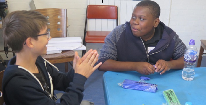 Two teenage boys work with plasticine to create characters for a movie as part of a creative respite programme for young carers