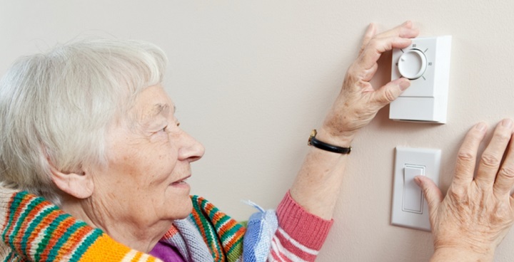 Older lady adjusting thermostat