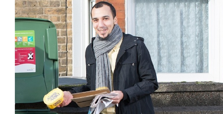 Street Champion Monir (author of this article) in scarf and coat recycling plastics in green wheelie bin