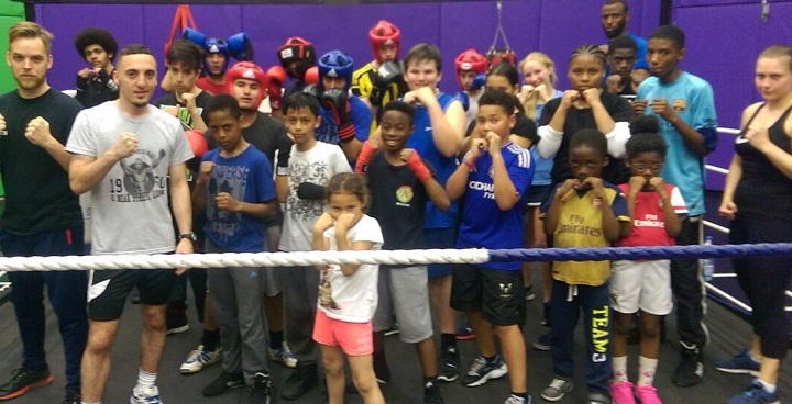 Boxing ring filled with young children, teenagers, and adults in boxing stances