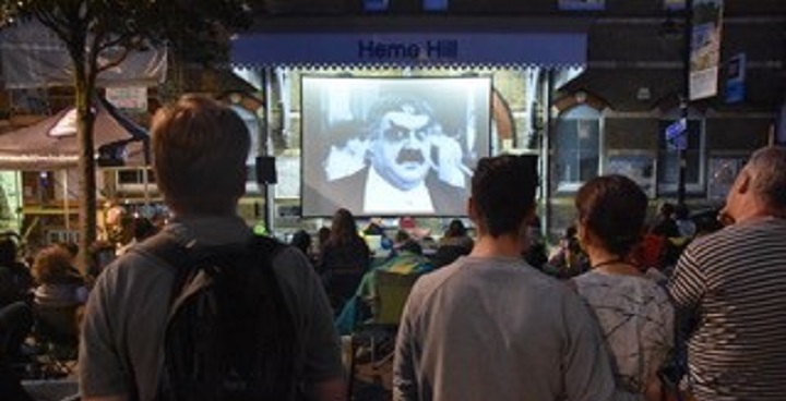 Audience watching black & white silent film in the open air at Herne Hill railway station