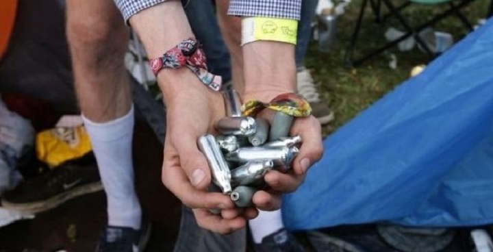 Hands of festival goers holding NOS canisters
