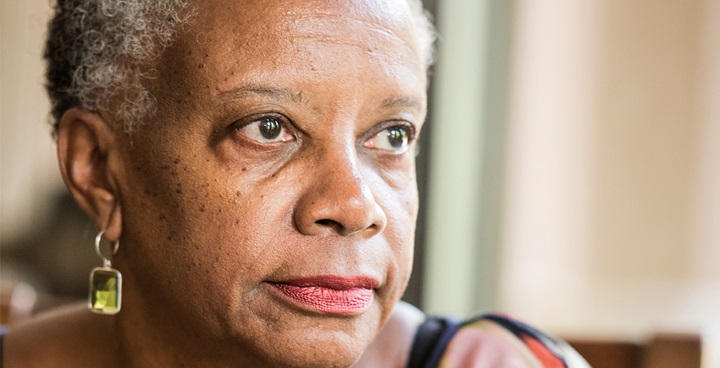 Older women's face with cropped grey hair, long earrings,