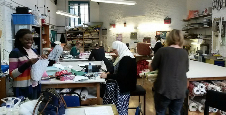 Caribbean, hajib-wearing and white woman among blots of cloth and sewing machines in 'all sewn up' class at Lady Margaret Hall Settlement