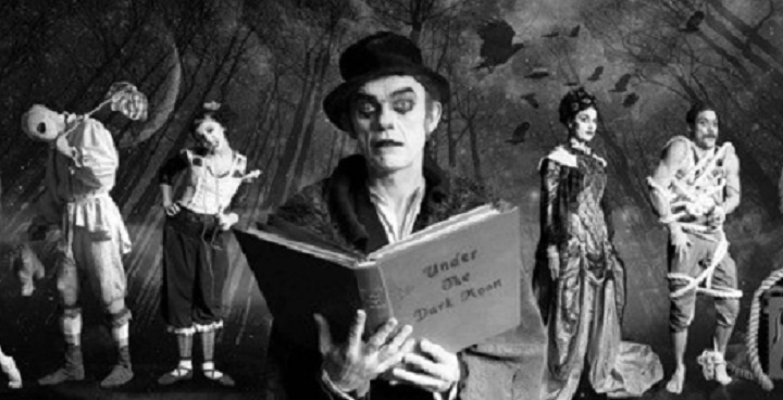 B&W photo of victrian-style circus performers incluing escapologist, clown in bwler hat reading from hardback book, woman in long dress