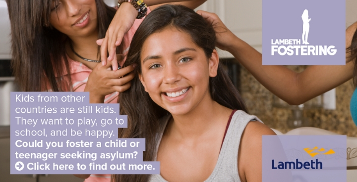 A young woman smiling at the camera whilst someone off shot does her hair.