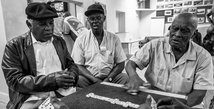 B&W photo by Jim Grover from 'Windrush Portrait f a Generation' exhibition - 3 caribbean senior citizens enjoy a game of dominoes