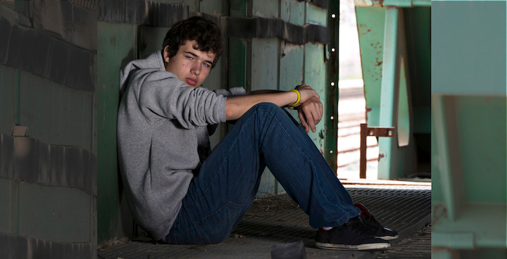 A young person sitting alone on a bridge.