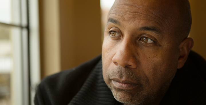 Image of a middle aged black man staring off camera looking sad.