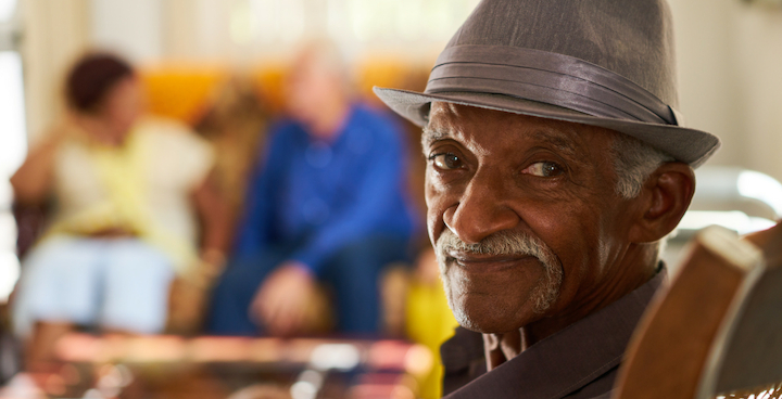 An elderly black man with a grey moustache and a grey trilby hat.