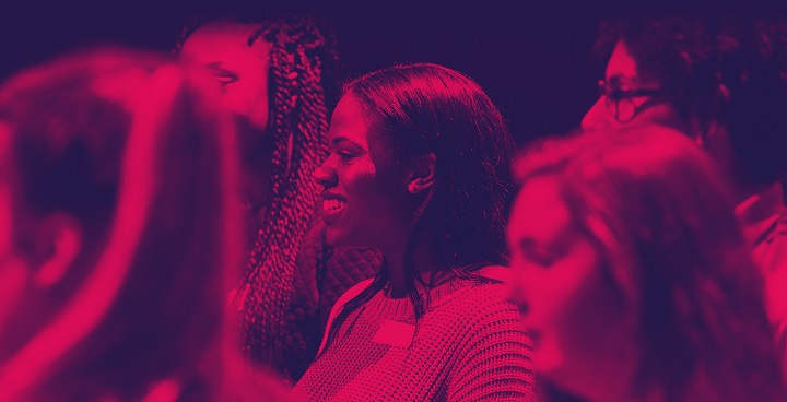 Red-tinted photo of young women in audience at 'immersive, theatrical' careers day for the creative industries