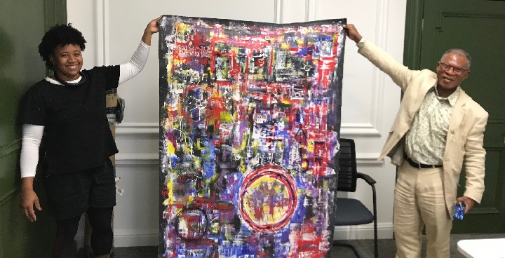 Artist Jackson Shuri and ex-mayor Donatus Anyanwu hold person-sized canvas of multicoloured abstract painting for show at Clapham Library Nov -Jan 2018