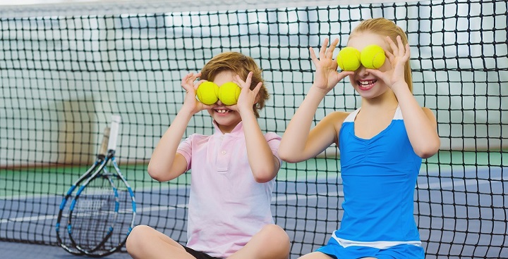two young girls (one in pink & one blue) using tennis balls as 'eyes'