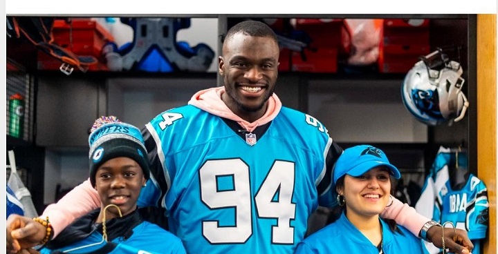 6 foot 6 NFL Player EfeObada with 2 young people from Stockwell taking part in Winter American Football coachng sessions in Larkall Park - all 3 are dressed in sky blue uniforms with white numbers