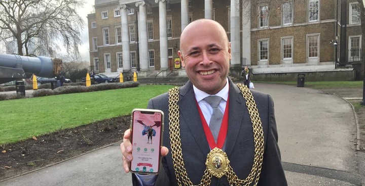 Mayor Wellbelove at the IMperial War Museum holding phone showing Pokemon on his screen. (Masyor Wellbelove is wearing chain of office)