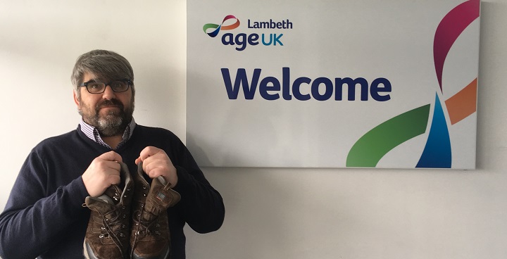Age UK Lambeth CEO GRaham holding trainers - pledges to walk at least 100 m iles in sponsored Lambeth Walk to raise funds for Age UK