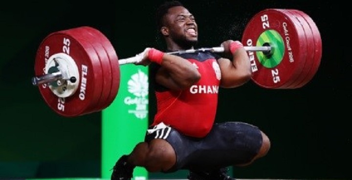 Wightlifter Forrester Osei in red top kneels to lift wights in competition