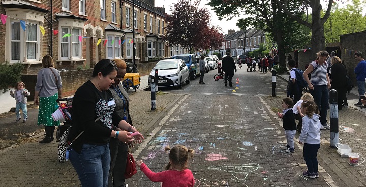 Children with adults playing in a closed street to cars - chalk drawings on road and children having lots of fun.