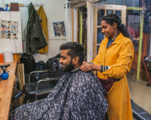 Man getting hair cut by barber in reliance arcade