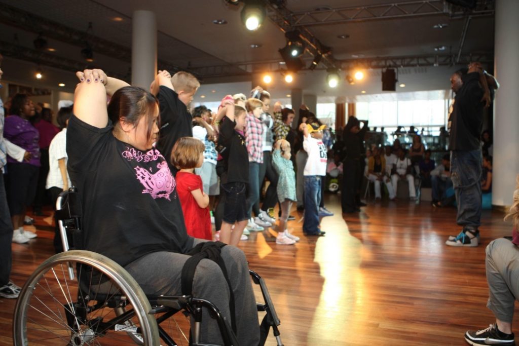 People ibncluding wheelchair uisers dancing in line