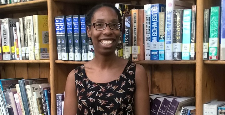 Librarian Zoey Dixon in front of Lambeth Libraries bookshelves