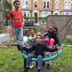 Group of kids sitting on shared swing in Lambeth adventure playground