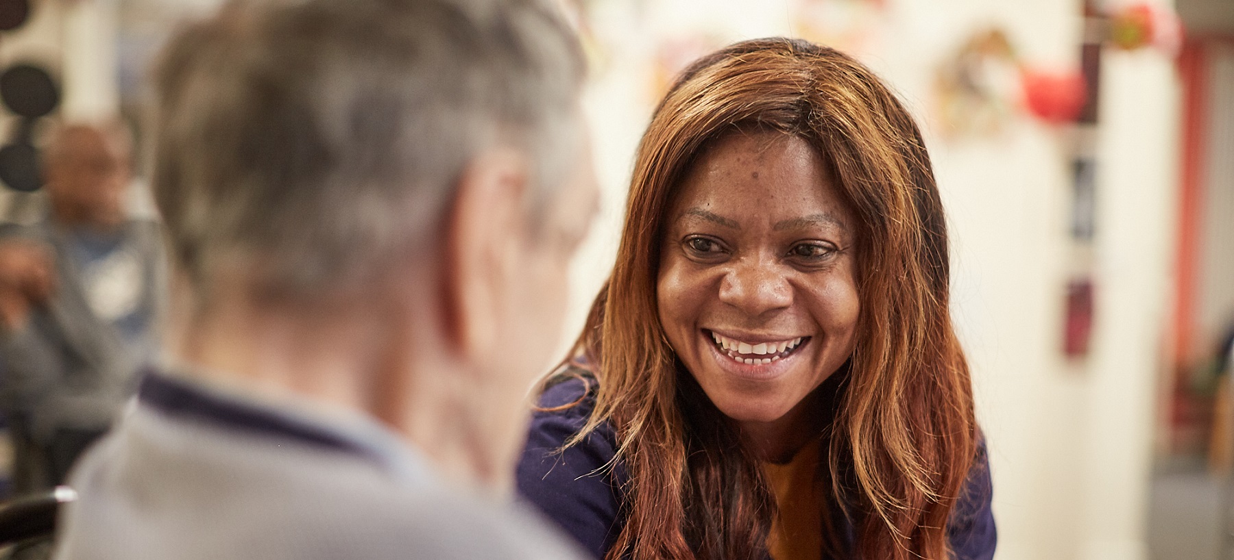 older white lady (back view) face to face with african-caribbean younger women smiling with long light brown hair