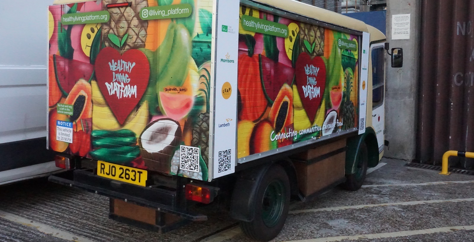 Healthy Living Platform's milk float with design of fruit and vegetables matching the mural in the Surplus Food Hub
