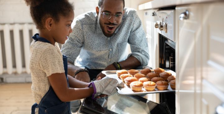 Young girl bakes while carer overlooks