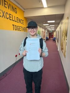 Young student hold his GCSE results and smiles