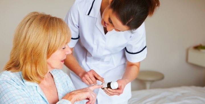 stock photo of woman talking to women in nurse's uniform and pointing at the instructions on pill bottle